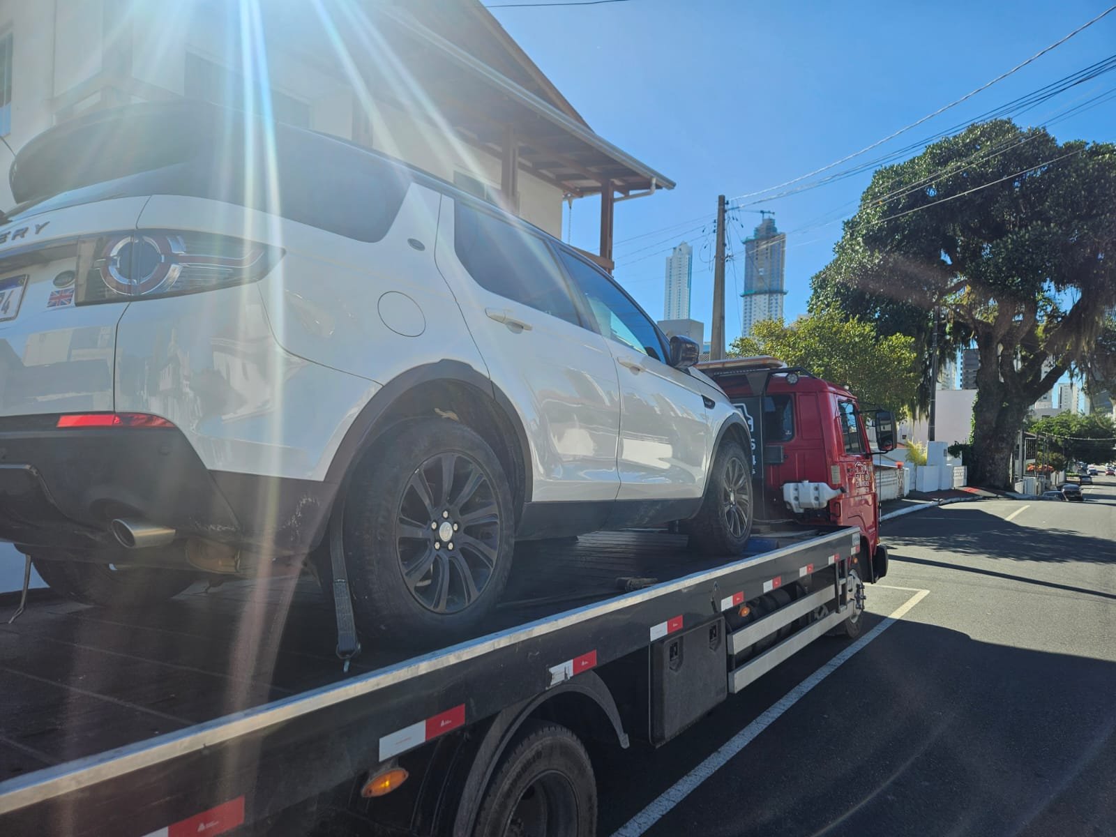 Guincho da CS Guinchos rebocando uma Land Rover com o skyline de Balneário Camboriú ao fundo